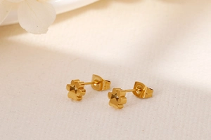 Vue rapprochée de boucles d'oreilles pattes de chien en acier plaqué or 18 carats sur fond