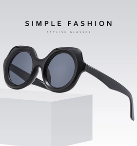 Detail of classic black oversized round sunglasses on a white geometric pedestal