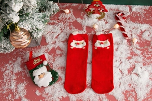 Detail of red Christmas cotton socks with a cute Santa Claus patch and festive knit texture