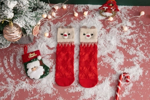 Close-up of red and beige knitted Christmas socks with cartoon reindeer on fake snow