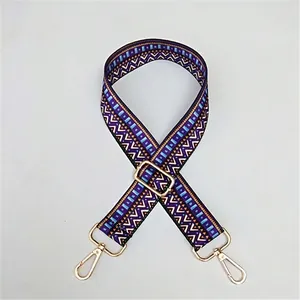 Close-up of geometric pattern crossbody strap with gold metal swivel hooks and buckles