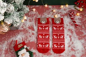 Detail view of red Christmas socks with 3D plush bear and white reindeer pattern