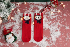 Close-up of festive red cotton socks with cute cartoon rabbit and Christmas ornaments