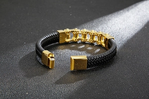 Close-up of black braided leather bracelet with golden chain link and magnetic clasp
