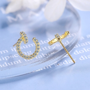 Minimalist gold stud earrings with cubic zirconia inlay on a blue background