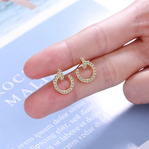 Elegant gold round stud earrings with pave-set zircon stones held on a fingertip