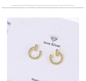 Macro shot of gold-plated nail-shaped earrings with sparkling cubic zirconia pavé setting