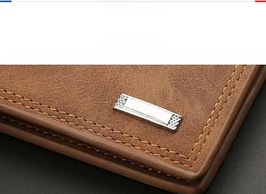 Macro detail of men's brown leather wallet showing silver logo and precise stitching