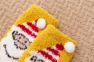 Close-up of thick yellow coral fleece winter sock with soft pom-poms and cute embroidery