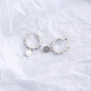 Macro shot of S925 sterling silver hoop earrings with sun pendants on white paper
