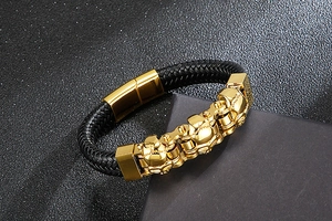 Macro shot of three golden skulls on black braided leather bracelet with magnetic clasp