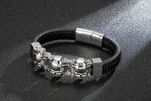Detail of men's black braided leather bracelet with silver skull and magnetic clasp
