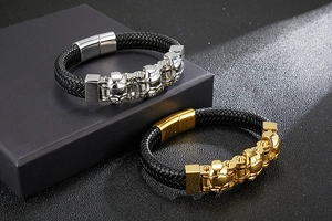 Detail of punk braided leather bracelets featuring steel skull charms and magnetic clasp