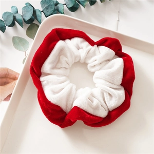 Chouchou de Noël en velours au design color block rouge et blanc sur un plateau