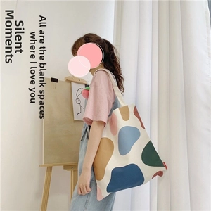 Detailed view of canvas tote bag with colorful abstract patterns on the shoulder