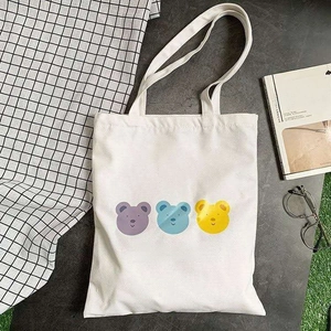 Close-up of white canvas tote bag with three naughty bears print and books
