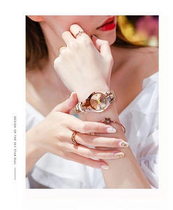 Detailed view of women's rose gold watch with starry dial and date window on wrist