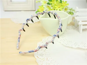 Detailed view of floral fabric wavy headband with inner teeth on a white ceramic cup