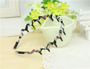 Detail of floral fabric wavy headband with black non-slip inner teeth against a white cup