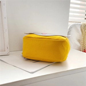 Detail view showing side and bottom of a yellow canvas backpack for toddlers