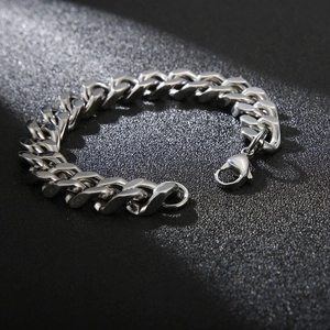 Polished silver cuban link bracelet with secure lobster clasp on textured black background