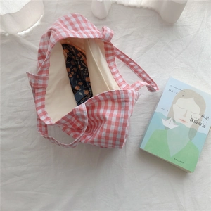 Detailed top view of pink checkered cotton tote bag with floral fabric inside on white background