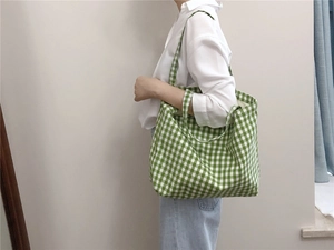 Detail of green and white gingham cotton tote bag worn over the shoulder in casual setting