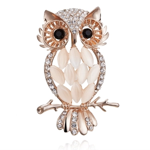 Detailed view of an owl brooch with rose gold finish, opal stones, and white rhinestones