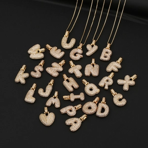 Pendentifs alphabet et cœur hip hop dorés sertis de zircons sur fond noir élégant
