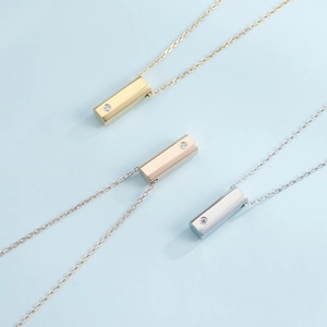 Three minimalist hexagonal prism pendant necklaces in gold, rose gold, and silver finishes