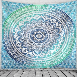 Detailed close-up of a teal and navy mandala tapestry hanging on a white brick wall