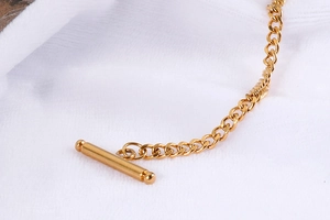 Macro detail of gold-plated OT toggle clasp closure on a minimalist chain necklace