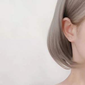 Detail of star and moon silver stud earrings worn on ear with polished finish