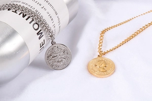 Dettaglio di collane a strati in oro e argento con ciondoli a moneta vintage in rilievo