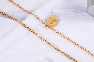 Dettaglio della collana a catena dorata a strati con ciondolo a moneta in stile vintage