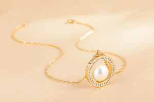 Détail macro du collier plaqué or avec anneau serti de diamants et pendentif perle blanche
