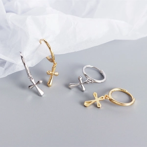 Close-up of minimalist S925 sterling silver cross charm hoop earrings in gold and silver
