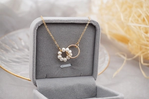 Detail of interlocking double rings with white pearls on a gold-plated O-chain necklace