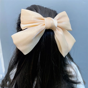 Close-up of a large champagne organza bow hair clip worn on a half-up hairstyle