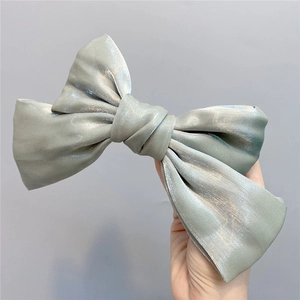 Detailed macro view of large organza bow hair clip with silky pearlescent light green fabric