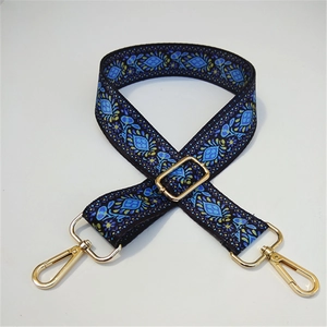 Macro detail of adjustable blue fabric strap with floral pattern and gold metal hooks