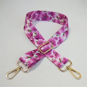 Detail of wide adjustable purse strap with pink cherry blossom pattern and gold hardware