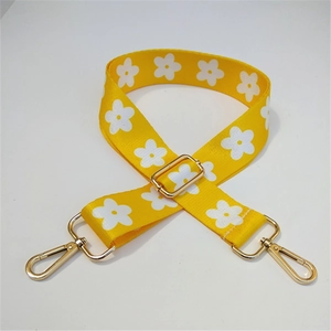 Close-up of yellow floral bag strap with white daisies and golden metal buckles