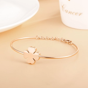 Minimalist rose gold clover bangle with adjustable chain and lobster clasp on white decor