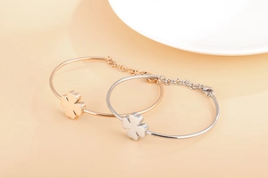 Detail of rose gold and silver clover bracelets featuring high-polish finish and adjustable chains