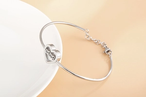 Detail of silver heart bracelet featuring mama engraving and adjustable lobster clasp closure