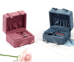 Pink and blue velvet travel jewelry boxes with ring slots shown on clean white background