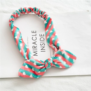 Détail d'un bandeau en velours à oreilles de lapin avec rayures rose-vert et cœurs blancs