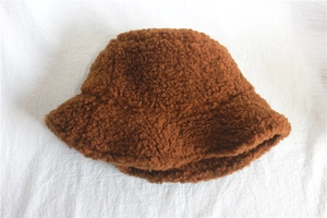 Detail view of deep brown lamb wool bucket hat texture on white fabric background