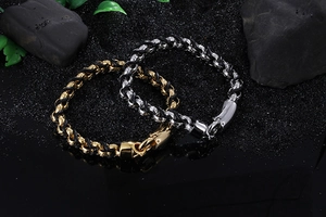 Close-up of gold and silver steel interlocking rings on black braided leather bracelets